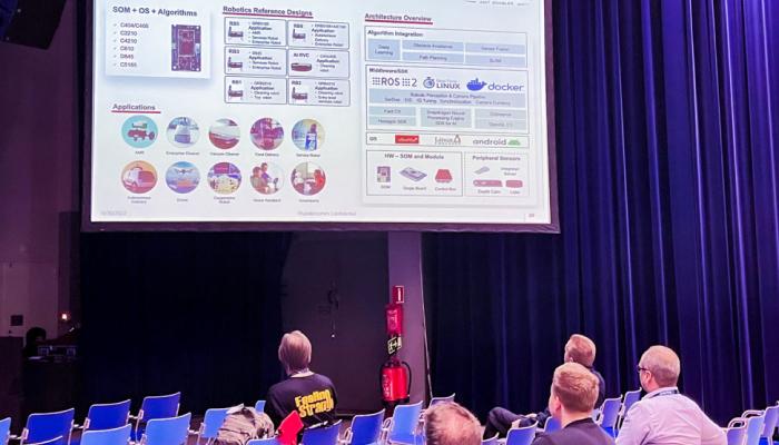 The expo's audience is looking upward the presentation depicting information about robotics.